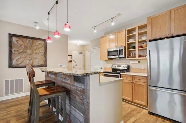 kitchen featuring visible vents, a kitchen bar, light wood-type flooring, appliances with stainless steel finishes, and open shelves