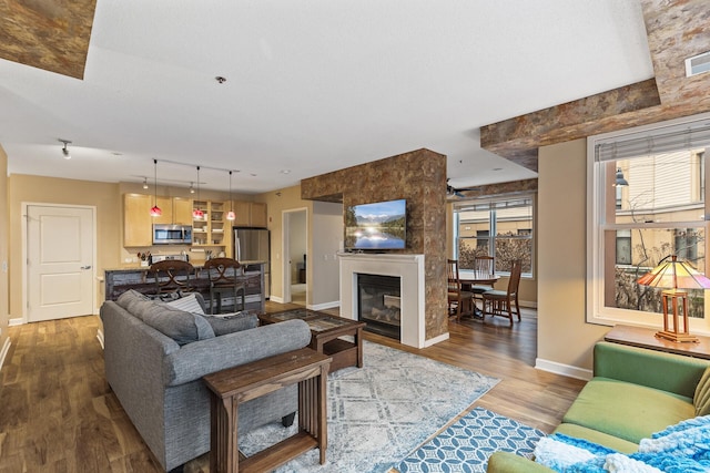 living room featuring visible vents, track lighting, baseboards, wood finished floors, and a glass covered fireplace