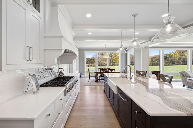 3175 Tuckborough Trl, Medina, MN 55356 - kitchen with stainless steel gas stovetop, crown molding, white cabinetry, backsplash, and a large island with sink