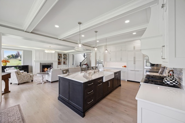 3175 Tuckborough Trl, Medina, MN 55356 - kitchen with white cabinetry, crown molding, a high end fireplace, backsplash, and light wood-type flooring