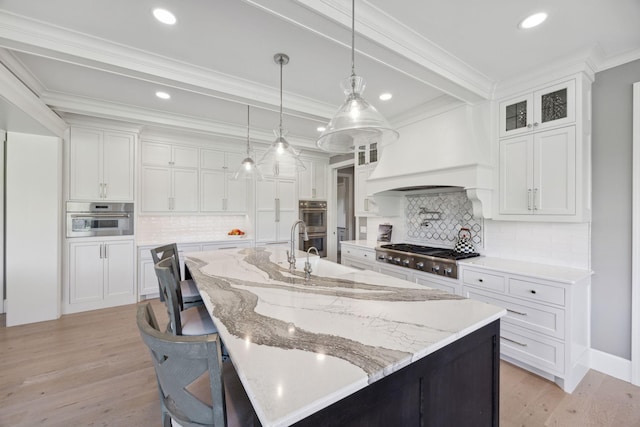3175 Tuckborough Trl, Medina, MN 55356 - kitchen featuring appliances with stainless steel finishes, light wood-style floors, white cabinets, a spacious island, and ornamental molding