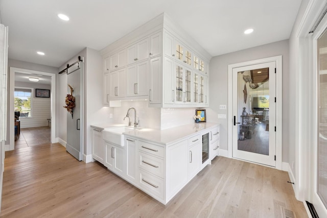 3175 Tuckborough Trl, Medina, MN 55356 - bar area featuring a barn door, light wood-style floors, and recessed lighting