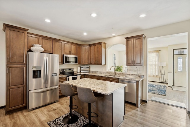 kitchen with a kitchen bar, light wood-type flooring, stainless steel appliances, sink, and a kitchen island