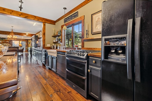 kitchen featuring dark hardwood / wood-style flooring, rail lighting, ornamental molding, stainless steel appliances, and decorative light fixtures