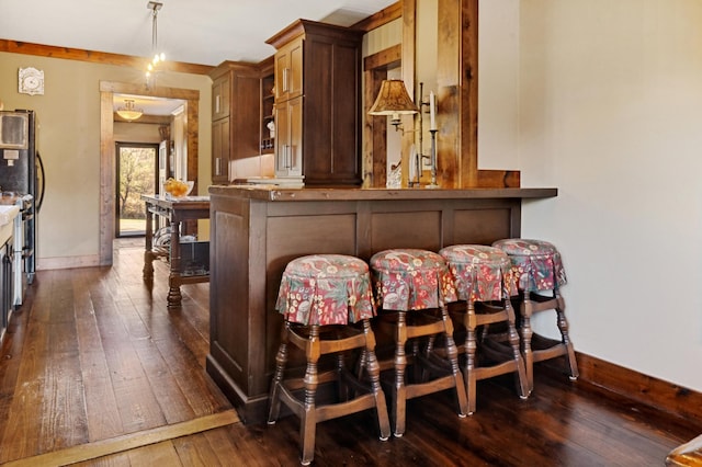 bar featuring dark hardwood / wood-style floors, refrigerator, and decorative light fixtures