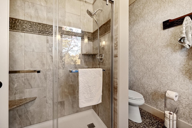 bathroom with a shower with door and toilet