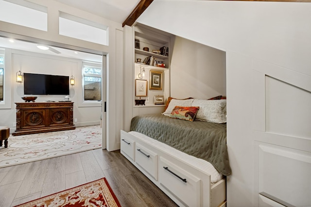 bedroom with hardwood / wood-style floors and beamed ceiling