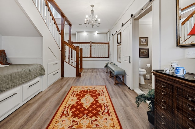 entryway with light wood-type flooring, a barn door, and a notable chandelier