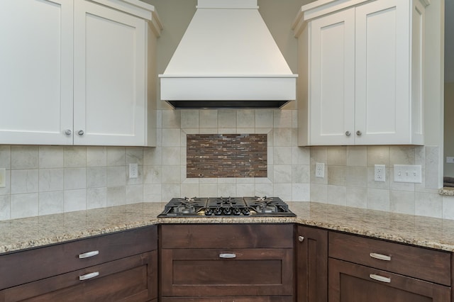 kitchen with premium range hood, dark brown cabinets, black gas stovetop, and white cabinetry