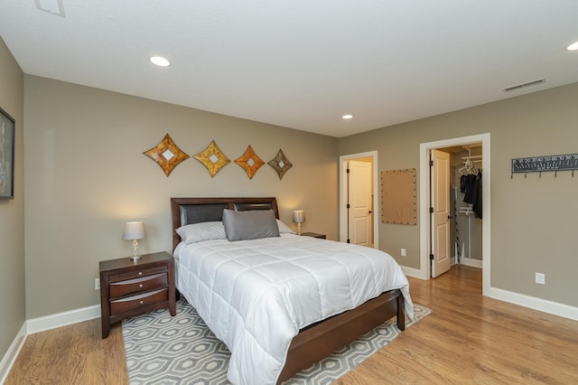 bedroom with baseboards, visible vents, a spacious closet, and light wood-style flooring