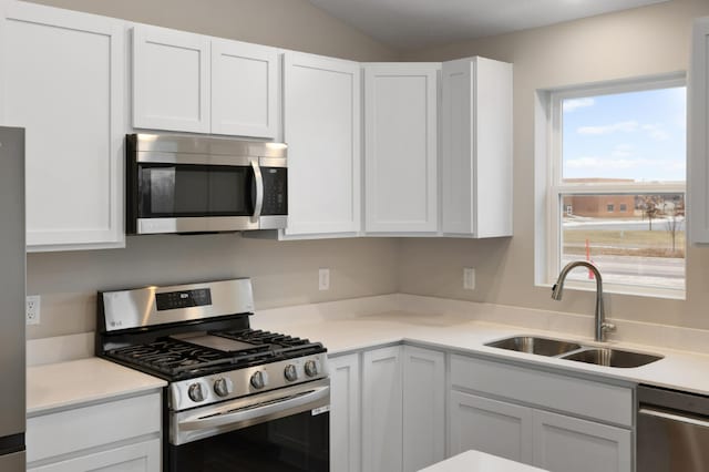 kitchen featuring white cabinetry, sink, stainless steel appliances, and lofted ceiling