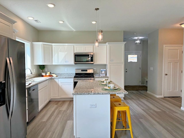 kitchen with sink, white cabinetry, decorative light fixtures, a kitchen island, and stainless steel appliances