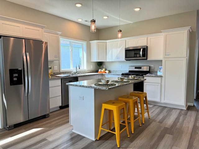 kitchen with white cabinetry, a kitchen island, dark stone counters, and appliances with stainless steel finishes