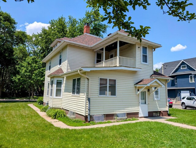 410 5th St, Montevideo, MN 56265 - view of front facade featuring a balcony, a front lawn, a chimney, and roof with shingles
