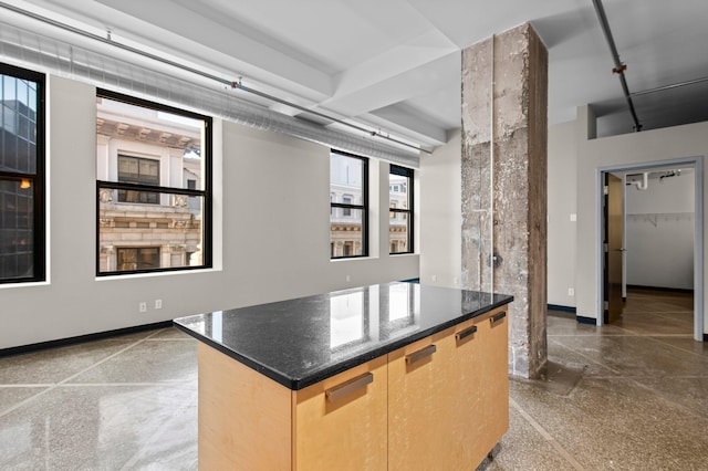 kitchen with a center island, light brown cabinetry, and dark stone counters