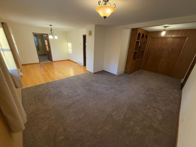 unfurnished room with light colored carpet and an inviting chandelier