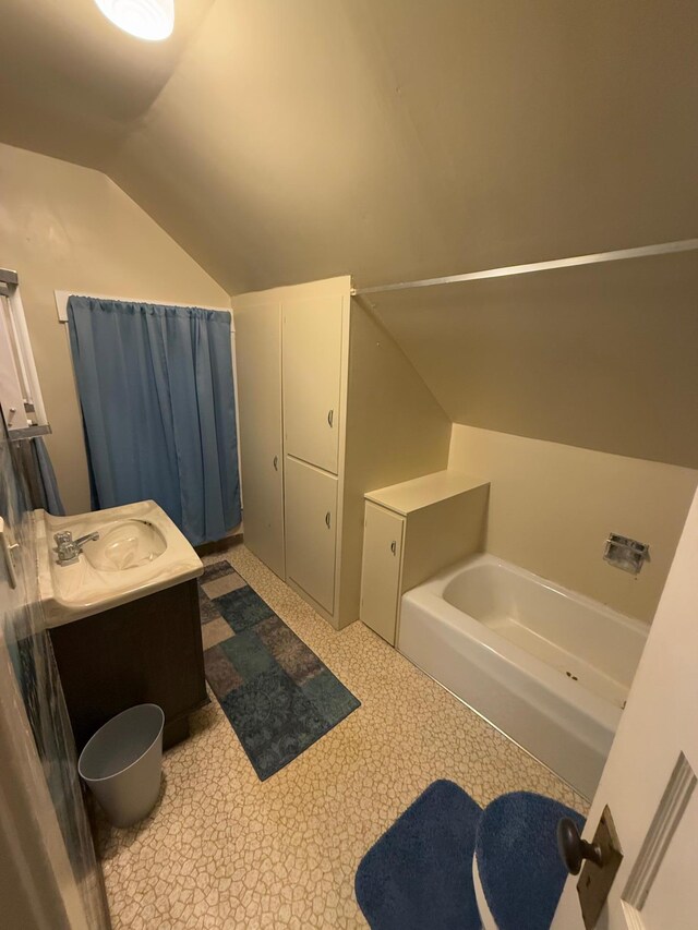 bathroom with vanity, a tub to relax in, and vaulted ceiling