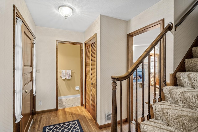 hallway with hardwood / wood-style flooring and a textured ceiling