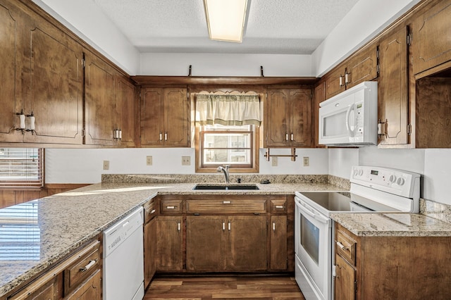 kitchen featuring sink, white appliances, light stone countertops, a textured ceiling, and dark hardwood / wood-style flooring