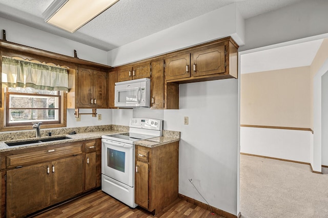 kitchen featuring sink, white appliances, light stone counters, a textured ceiling, and dark hardwood / wood-style flooring