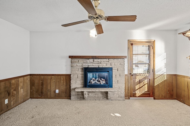 unfurnished living room featuring light carpet, a fireplace, wooden walls, and a textured ceiling