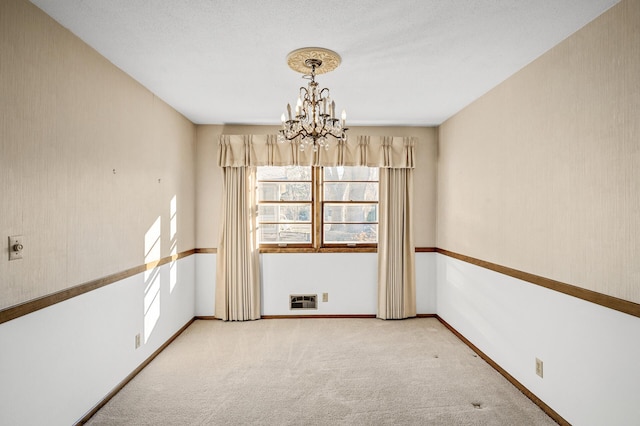 unfurnished room with an inviting chandelier and light carpet