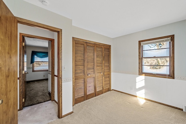 unfurnished bedroom with light colored carpet and a closet