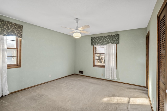 unfurnished bedroom featuring multiple windows, light carpet, ceiling fan, and a closet