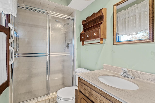 bathroom featuring vanity, a shower with door, and toilet