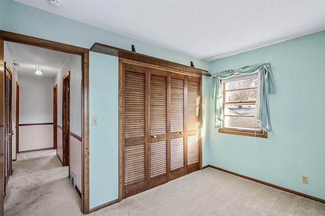 unfurnished bedroom with light colored carpet, a textured ceiling, and a closet