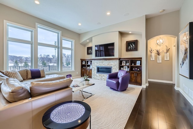 living room featuring a stone fireplace and dark hardwood / wood-style floors