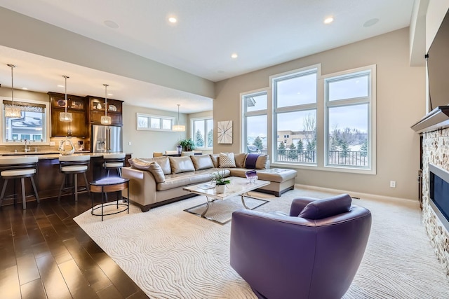 living room with dark wood-type flooring, a fireplace, and sink