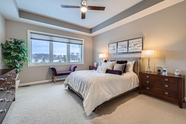 bedroom featuring ceiling fan, a tray ceiling, and light colored carpet