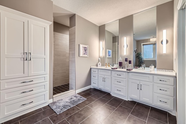 bathroom with tiled shower, vanity, and a textured ceiling