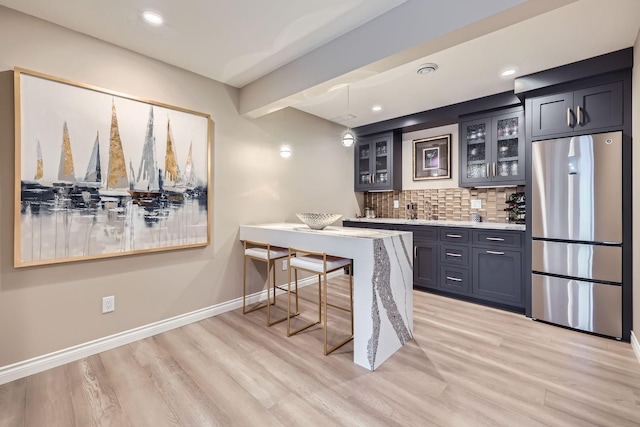 bar featuring pendant lighting, backsplash, stainless steel refrigerator, and light hardwood / wood-style floors