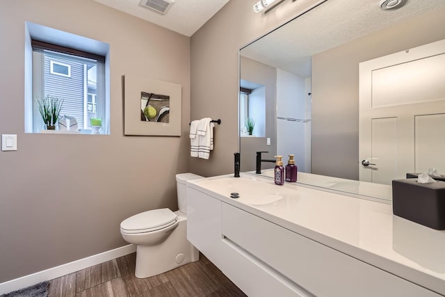 bathroom featuring vanity, hardwood / wood-style floors, a textured ceiling, and toilet