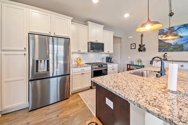 kitchen with white cabinetry, sink, stainless steel appliances, and decorative light fixtures