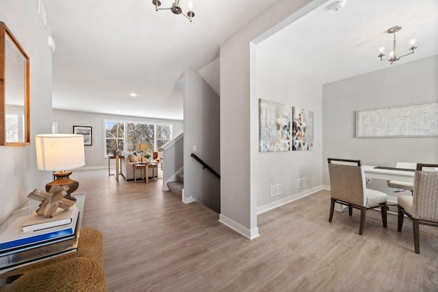 corridor featuring an inviting chandelier and light hardwood / wood-style flooring