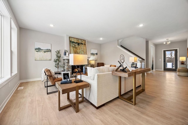 living room featuring a fireplace, a notable chandelier, and light hardwood / wood-style flooring