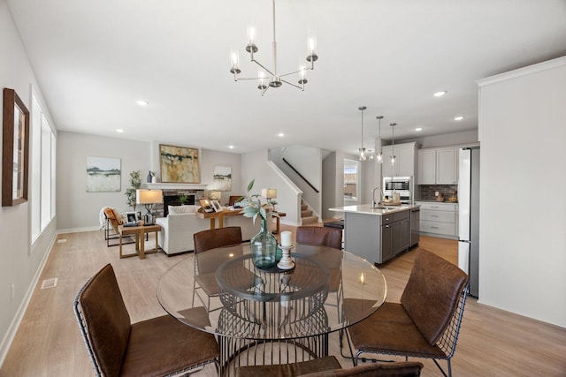 dining space with light wood-type flooring, a notable chandelier, and sink