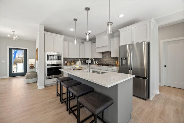 kitchen with sink, white cabinets, hanging light fixtures, a center island with sink, and appliances with stainless steel finishes