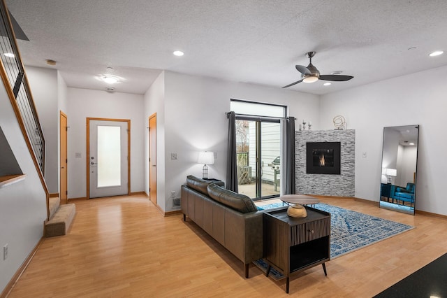 living room featuring a textured ceiling, light wood-type flooring, and ceiling fan