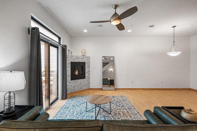 living room featuring a fireplace, ceiling fan, and light hardwood / wood-style flooring