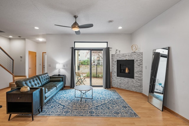 living room with ceiling fan, light hardwood / wood-style floors, and a textured ceiling