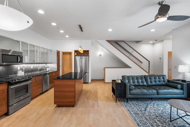 kitchen with light wood-type flooring, backsplash, stainless steel appliances, sink, and a center island