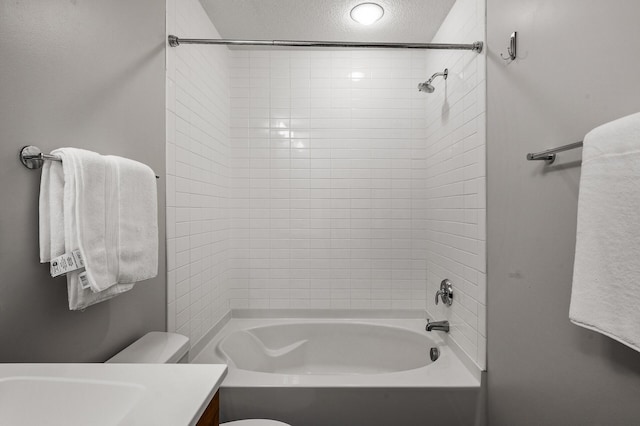 full bathroom with vanity, a textured ceiling, toilet, and tiled shower / bath