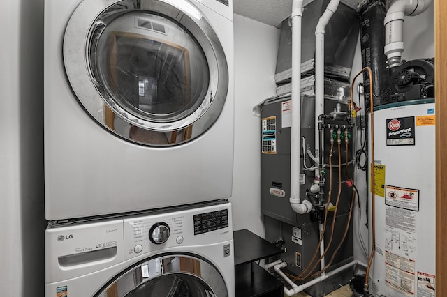 clothes washing area featuring stacked washer / drying machine, gas water heater, and a textured ceiling