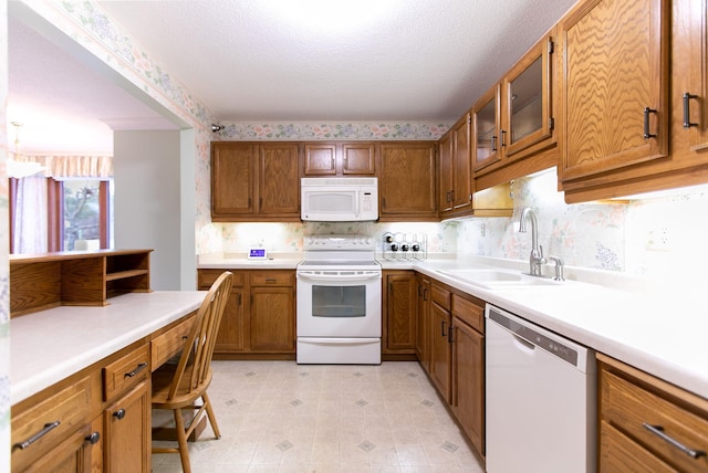 kitchen with a textured ceiling, white appliances, hanging light fixtures, and sink