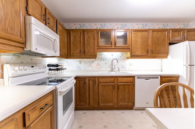 kitchen with a textured ceiling, white appliances, and sink