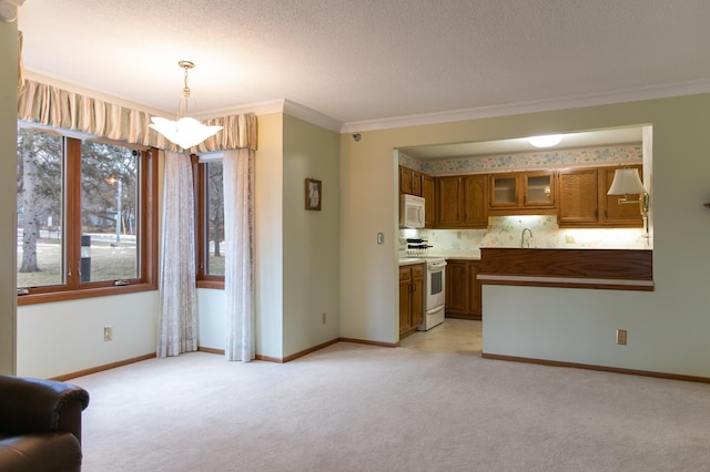 kitchen with kitchen peninsula, pendant lighting, white appliances, light carpet, and ornamental molding